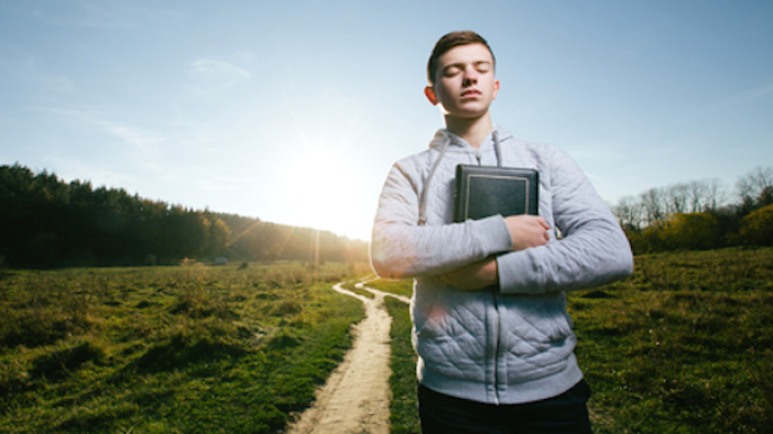 Young-man-holding-Bible-in-a-park-Shutterstock